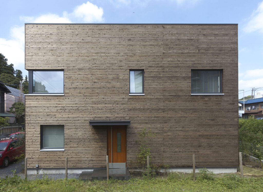 Exterior view of the first certified Passive House in Kamakura, Japan. The building is completely enclosed in a gorgeous, cool-toned timber cladding. 